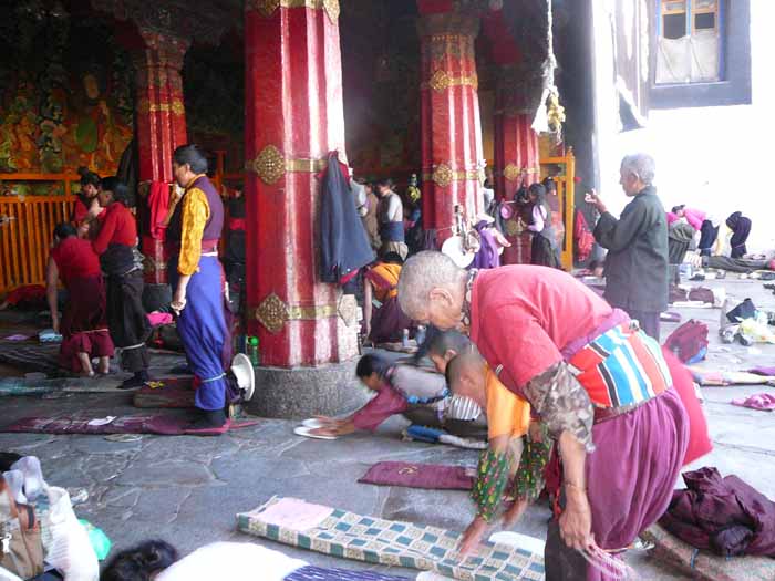 Буддийские паломники из Непала, Индии и Китая простираются перед входим в хрм Джоканг . Джоканг является самым почитаемым религиозным сооружением в Тибете. Кора(ритуальный обход)  вокруг Джоканга проходит по огибающей его улице. Кора движется по часовой стрелке, вовлекая в себя тысячи людей( и нас в том числе), произносящих мантры и обходящих храм от восхода до заката. - Тибет 2006