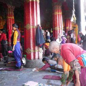 Буддийские паломники из Непала, Индии и Китая простираются перед входим в хрм Джоканг . Джоканг является самым почитаемым религиозным сооружением в Тибете. Кора(ритуальный обход)  вокруг Джоканга проходит по огибающей его улице. Кора движется по часовой стрелке, вовлекая в себя тысячи людей( и нас в том числе), произносящих мантры и обходящих храм от восхода до заката. - Тибет 2006