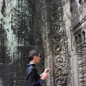 Та Пром. На стенах храмов - гид показывает изображения динозавров и невиданных животных - Путешествие  по Камбодже, декабрь 2012г.